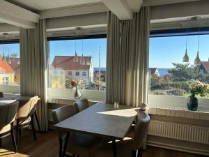 a dining room with a table and chairs and large windows at Hotel Villum in Sandvig