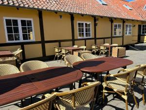 an outdoor patio with tables and chairs and a building at Hotel Villum in Sandvig