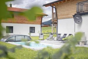 a group of chairs and a pool in front of a house at Luxalps- BergZeit- Inzell- Sommerpool- Sauna- Wandern- Chiemgau Card in Inzell