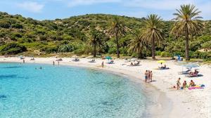 a group of people on a beach near the water at La Rosa dei Venti in SantʼAntìoco
