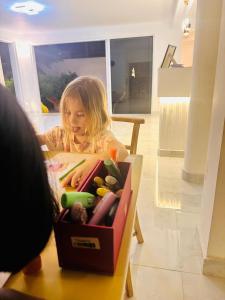 a little girl sitting in a box of toys at La Costa Hotel 15 Min from Airport,Free High-Speed WiFi, Spa Bath, Pool & Restaurant in Katunayaka