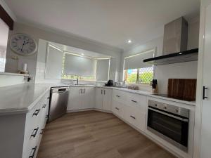 a kitchen with white cabinets and a clock on the wall at Midtown Oasis - Sleeps 9 in Scarness