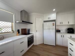 a kitchen with white cabinets and a white refrigerator at Midtown Oasis - Sleeps 9 in Scarness
