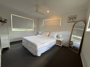 a bedroom with a white bed and a mirror at Midtown Oasis - Sleeps 9 in Scarness