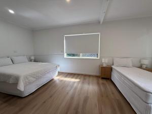 a white room with two beds and a window at Midtown Oasis - Sleeps 9 in Scarness