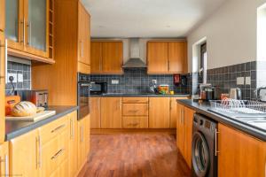a large kitchen with wooden cabinets and a washer at Kernow House in Croyde