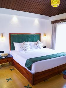 a bedroom with a large bed with a green headboard at Anaasa Resorts in Tiruvannāmalai +35 photos