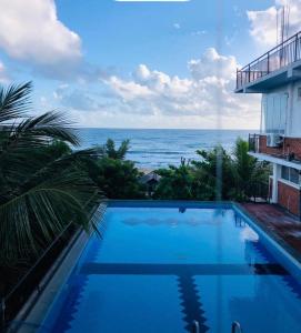 a swimming pool with a view of the ocean at D & D Beach Resort in Trincomalee