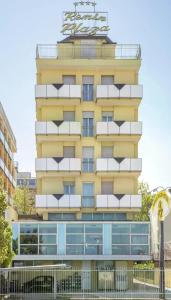 a tall yellow building with a clock on top of it at Hotel Remin Plaza in Rimini