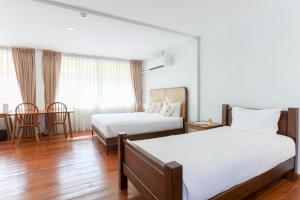 a hotel room with two beds and a table at Samer Boutique Stay in Bangkok