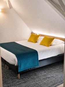 a bed with yellow pillows in a room at Aux Deux Clefs - Hôtel Restaurant Groff in Biesheim
