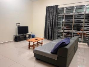 a living room with a couch and a tv and a table at Homestay 76 in Mersing