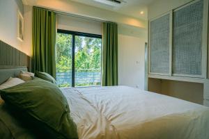 a bedroom with a large bed and a large window at Tabebuia House ทาเบบูย่าเฮ้าส์ in Pathiu