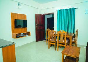 a living room with a dining room table and a television at Ocean Breeze Service Apartment in Malpe