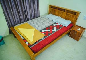 a wooden bed in a room with a red and yellow blanket at Ocean Breeze Service Apartment in Malpe