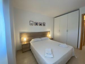 a bedroom with a white bed with two towels on it at Apartament Sara in L'Eucaliptus