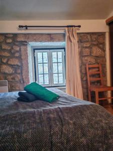 a bedroom with a bed with a green pillow on it at Stone House - Waterfalls, Nature Stay in Louriçal do Campo