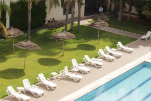 Draufsicht auf einen Pool mit Liegestühlen und Sonnenschirmen in der Unterkunft Eventi Club by cité des sports adarissa in Fès