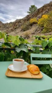 a cup of coffee and a croissant on a cutting board at vardzia Guesthouse Mtkvari in Nak'alak'evi