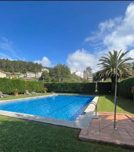 a swimming pool in a yard with a palm tree at Atico con terraza al mar in Mogro