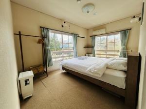 a bedroom with a large bed and two windows at Hakuba Snow Fox in Hakuba