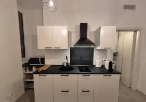 a kitchen with white cabinets and a black counter top at Casetta della Lupa in Cernusco sul Naviglio +11 photos