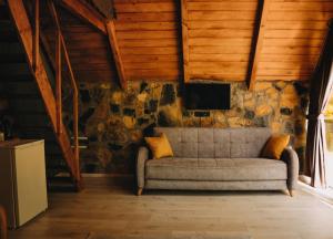 a couch in a room with a stone wall at Yeşil Cennet Tatil Köyü in Pazar