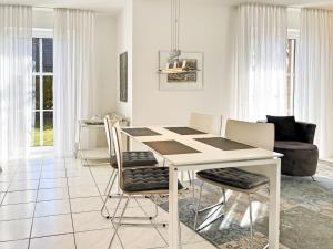 a white dining room with a white table and chairs at Windwatt 2 in Zingst