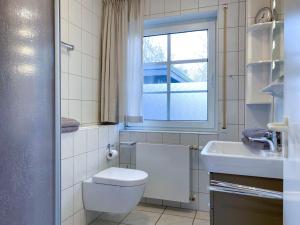 a bathroom with a toilet and a sink and a window at Windwatt 2 in Zingst +3 photos