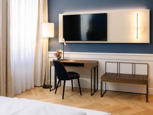 a hotel room with a desk and a tv on a wall at Hotel Kaiserhof Wien in Vienna