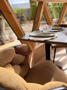 a table with plates and glasses and a chair at L'Échappée Bulle - Dôme & jacuzzi - Bastogne Centre in Bastogne +13 photos
