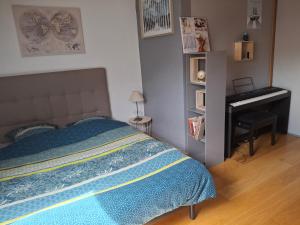 a bedroom with a bed and a desk and a piano at La Maison des Coeurs in Attignat-Oncin