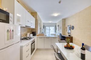 a kitchen with white cabinets and a table with a bowl of fruit at Staytopus Offshore Marsalforn Budget Room for Divers & Travelers in Marsalforn