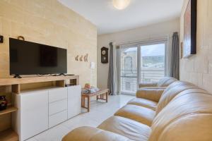 a living room with a couch and a flat screen tv at Staytopus Offshore Marsalforn Budget Room for Divers & Travelers in Marsalforn