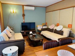 a living room with couches and a flat screen tv at 風まち in Yawatano +26 photos