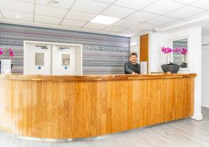 a man standing at the reception desk of a dental office at Sandy Lodge Hotel Newquay in Newquay