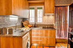 a kitchen with wooden cabinets and a sink and a window at Casa Rural con piscina privada y jardines - LA CASILLA in Cájar