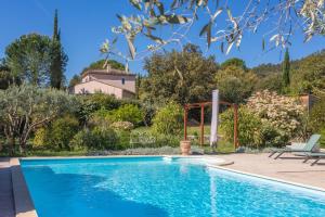 Ein Swimmingpool in einem Garten mit einem Haus im Hintergrund in der Unterkunft Bastidon Cotignac in Cotignac + 18 Fotos