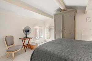ein Schlafzimmer mit einem Bett, einem Stuhl und einem Spiegel in der Unterkunft Bastidon Cotignac in Cotignac