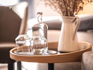 a glass bottle on a wooden table with a vase at Hotel Alpenblick in Weissbad