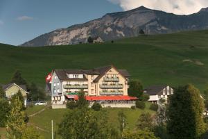 a hotel on a hill with a mountain in the background at Hotel Alpenblick in Weissbad +32 photos