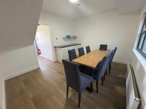 a dining room with a wooden table and blue chairs at Cunninghame 3 in Beith