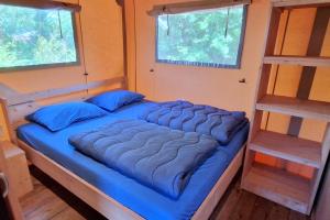 a large blue bed in a room with two windows at Glamping Drouwenerzand in Drouwen