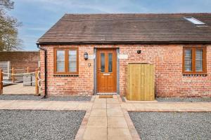 a red brick house with a wooden door at Host & Stay - Beagle Barn in Withington
