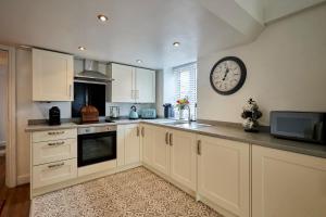 a kitchen with white cabinets and a clock on the wall at Host & Stay - Beagle Barn in Withington