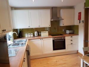 a kitchen with white cabinets and a stove top oven at Number 4, Loch Shiel View in Glenfinnan