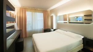 ein Schlafzimmer mit einem weißen Bett und einem Spiegel in der Unterkunft San Ranieri Hotel - Meetings & Pool in Pisa