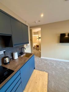 a kitchen with blue cabinets and a living room at Grindal Studio Apartments - Newly Opened Luxury Accommodation in St Bees