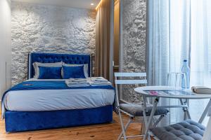 a bedroom with a blue bed and a table at Celtic Lodge - Guest House in Viseu