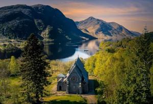an old church on the shore of a lake with mountains at Number 4, Loch Shiel View in Glenfinnan